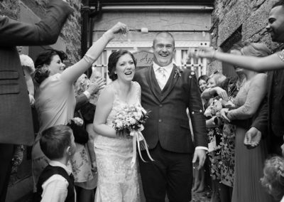 a bride and groom walking through confetti at Chateau Rhianfa