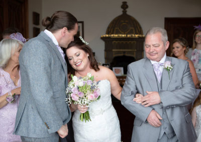 a groom kissing the top of his bride's head at the alter at Chateau Rhianfa