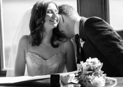 a groom at Chateau Rhianfa kissing his bride's shoulder by Anglesey wedding photographer Gill Jones