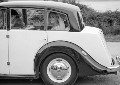 the bride looking through the wedding car at Penmon Priory