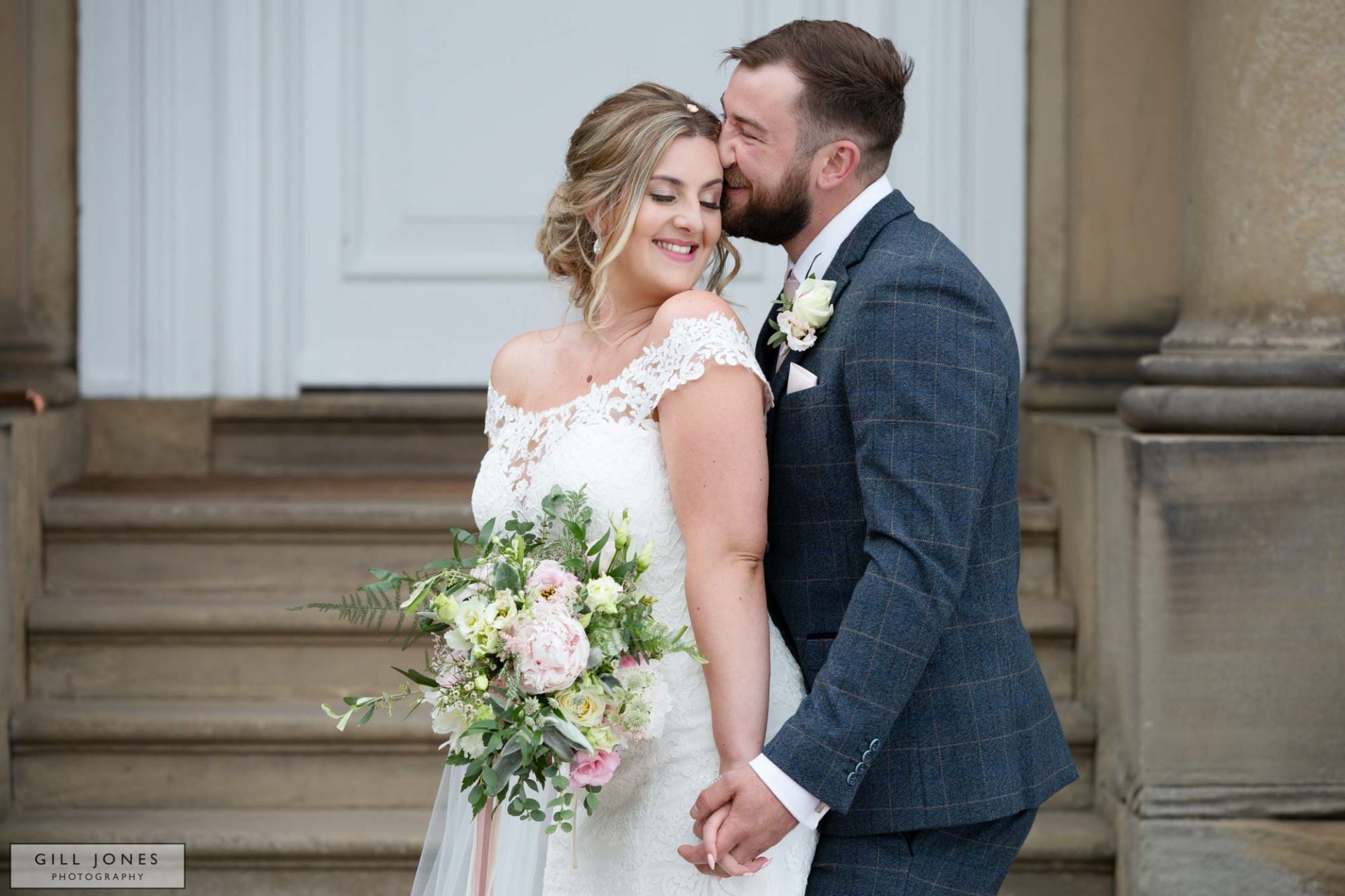 Bride and groom caressing by the steps to Iscoyd Park