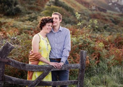 couple caressing whilst standing by a beautiful gate at Holyhead Breakwater Park by Anglesey wedding photographer Gill Jones