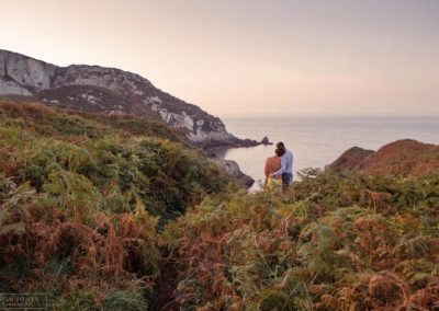back view of couple as they look out towards the Irish sea at Holyhead Breakwater Park, lots of ferns in the foregroundcouple sitting side by side on steps around Holyhead Break water park by Anglesey wedding photographer Gill Jones