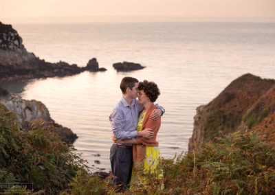 couple facing one another, his nose resting against her forehead, the Irish sea is in the background at Holyhead Breakwater Park bycouple sitting side by side on steps around Holyhead Break water park by Anglesey wedding photographer Gill Jones