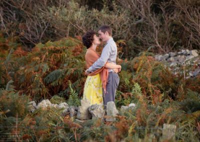 Couple standing facing one another, nose to nose amongst the ferns at Holyhead Breakwater Parkcouple sitting side by side on steps around Holyhead Break water park by Anglesey wedding photographer Gill Jones
