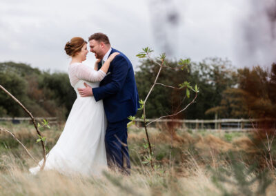 bride and groom hugging by the pond at Henblas