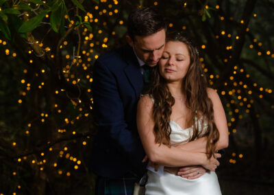 Bride and groom hugging surrounded by fairt lights at Henblas