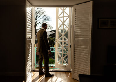 a groom looks out of the doors of the Salutation suite at Portmeirion Village by Anglesey wedding photographer Gill Jones Photography