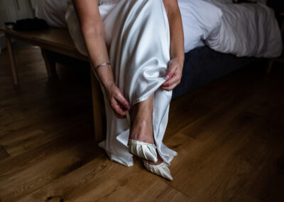 the bride is wearing pointed ivory coloured shoes she pulls her skirt around her ankles by Anglesey wedding photographer Gill Jones Photography