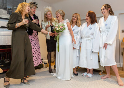 a bride stands with her female friends as she prepares for her wedding by Anglesey wedding photographer Gill Jones Photography