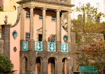 a groom stands on the balcony of the Salutation suite at Portmeirion Village by Anglesey wedding photographer Gill Jones Photography