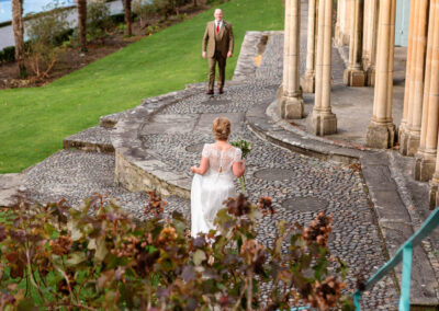 a bride approaches her groom at Portmeirion Village by Anglesey wedding photographer Gill Jones Photography