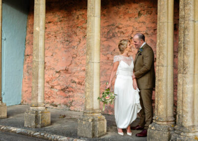 a groom holds his bride by the wrist as if to steal a kiss at Portmeirion Village by Anglesey wedding photographer Gill Jones Photography