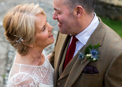 a bride and groom stand chest to chest, smiling with noses almost touching by Anglesey wedding photographer Gill Jones Photography