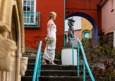 we see a bride's profile as she stands with a burnt orange coloured wall in the background at Portmeirion Village by Anglesey wedding photographer Gill Jones Photography