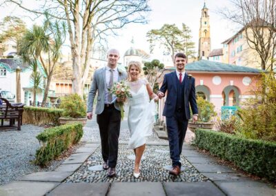 a bride walks towards her ceremony at Portmeirion Village flanked by her two sons by Anglesey wedding photographer Gill Jones Photography
