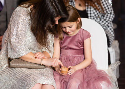 a young bridesmaid holds a wooden box with an inscription on it a woman traces the letters with her finger by Anglesey wedding photographer Gill Jones Photography