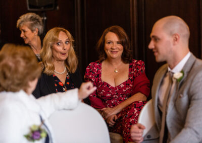 guests chat at a wedding ceremony one guest pull a face full of surprise by Anglesey wedding photographer Gill Jones Photography