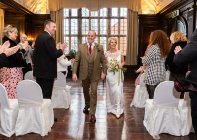 a bride and groom walk down the aisle at Hercules Hall at Portmeirion Village by Anglesey wedding photographer Gill Jones Photography