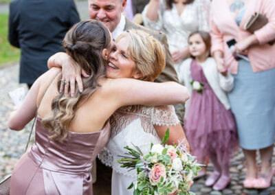 a bride hugs one of her wedding guests whilst others smile and look on at Portmeirion Village by Anglesey wedding photographer Gill Jones Photography