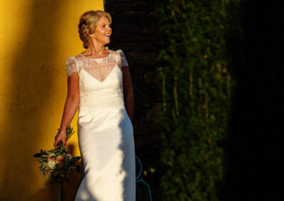 a bride leans against a sun drenched wall in Portmeirion Village by Anglesey wedding photographer Gill Jones Photography