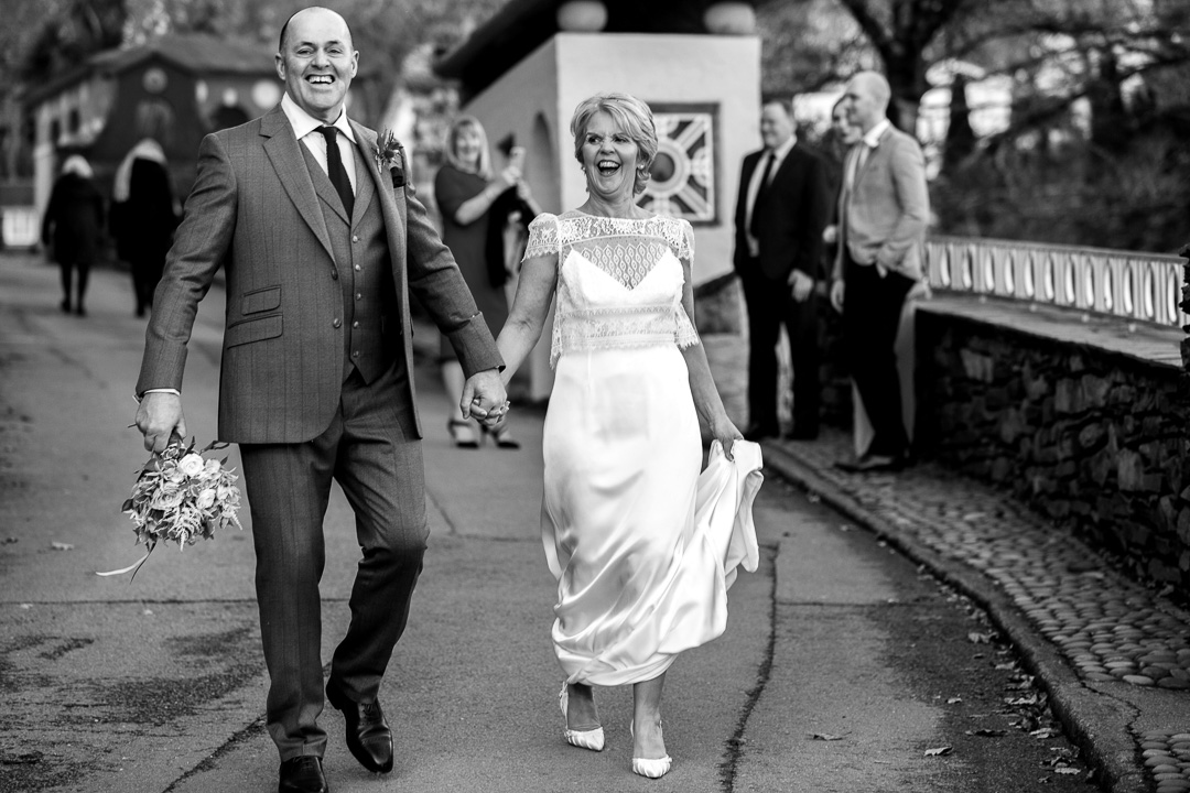 Laughing bride and groom walking through Portmeirion