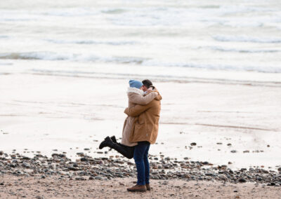 man lifts his new fiancé off the ground in celebration of her accepting his proposal of marriage