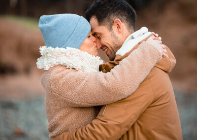 newly engaged couple hugging closely as the woman kisses her fiancé's nose by Anglesey wedding photographer Gill Jones