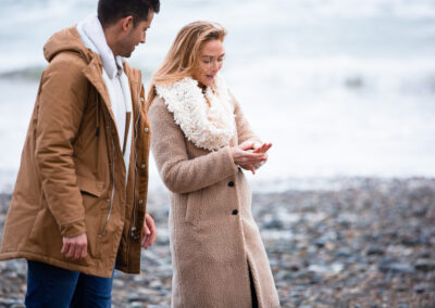 woman marvels at her new engagement ring with her fiancé looking on by Anglesey wedding photographer Gill Jones
