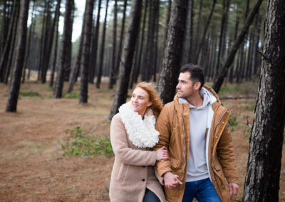 couple walking through Newborough forest arm in arm by Anglesey wedding photographer Gill Jones