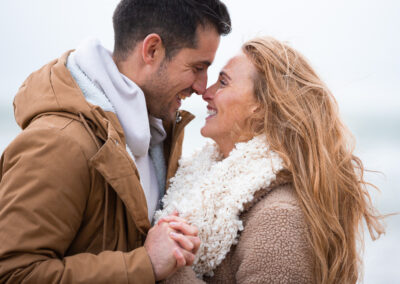 newly engaged couple nose to nose near Llanddwyn island by Anglesey wedding photographer Gill Jones