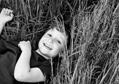 young boy lying down in the grass smiling towards the camera