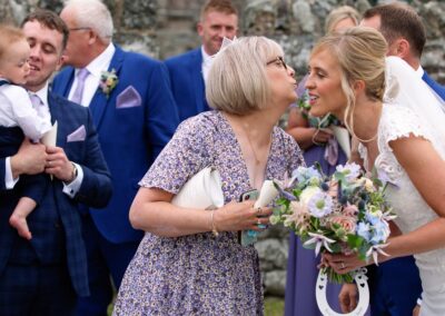 a friend reaching the kiss the brideat St. Mary's Church , Caerhun by Anglesey wedding photographer Gill Jones Photography