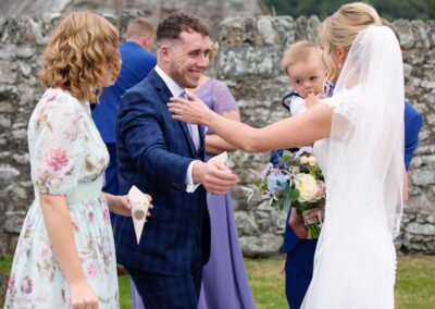 a guest reaching out the the bride to congratulate herat St. Mary's Church , Caerhun by Anglesey wedding photographer Gill Jones Photography