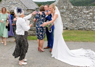 an aunt reaching out to the bride to wish her wellat St. Mary's Church , Caerhun by Anglesey wedding photographer Gill Jones Photography
