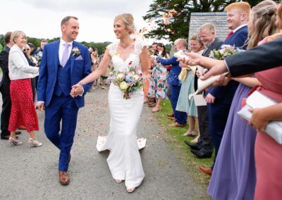 Bride and Groom walking under confetti at St. Mary's Church , Caerhun by Anglesey wedding photographer Gill Jones Photography