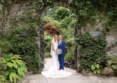 Bride and groom under the entrance arch to Bodnant Gardens by Anglesey wedding photographer Gill Jones Photography