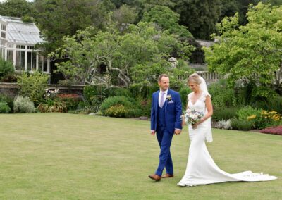 bride and groom walking across the lawn at Bodnant Gardensbride and groom standing nose to nose in the rose garden at Bodnant Gardensby Anglesey wedding photographer Gill Jones