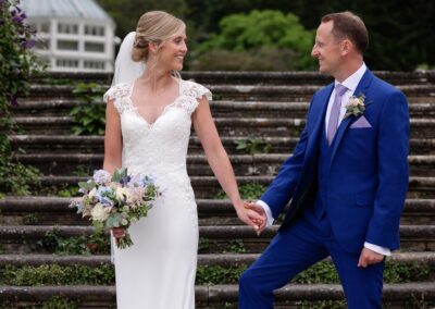 bride and groom holding hands by the steps at Bodnant Gardensbride and groom standing nose to nose in the rose garden at Bodnant Gardensby Anglesey wedding photographer Gill Jones