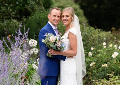 bride and groom standing nose to nose in the rose garden at Bodnant Gardensby Anglesey wedding photographer Gill Jones