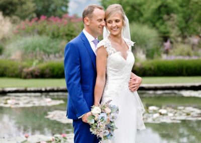 the bride and groom suggling in front of the pond at Bodnant Gardensby Anglesey wedding photographer Gill Jones