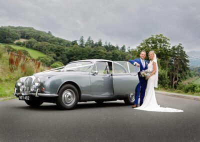 bride and groom stand by the Daimler 250 at Bodnant Food Centreby Anglesey wedding photographer Gill Jones