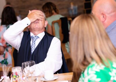 a guest covers his eyes during the speeches at Bodnant Food Centreby Anglesey wedding photographer Gill Jones