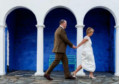 bride and groom walking swiftly at Portmeirion villageby Anglesey wedding photographer Gill Jones Photography
