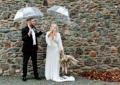 Bride and Groom sheltering under umbrellas on Angleseyby Anglesey wedding photographer Gill Jones Photography