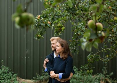 Couple standing under an apple tree by a green barn by Anglesey wedding Photographer Gill Jones