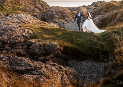 bride and groom walking along the cliffs in Trearddur Bayby Anglesey wedding photographer Gill Jones