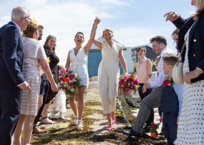 two brides walking down the slip way on Trearddur Bay by Anglesey wedding photographer Gill Jones Photography