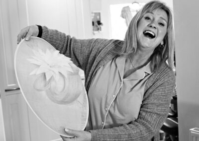 the bride's mother holds her hat and laughs by Anglesey wedding photographer, North Wales, Gill Jones Photography