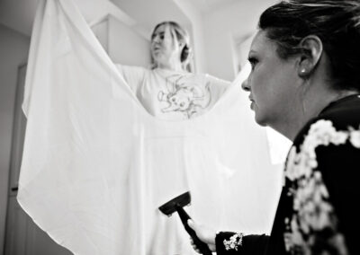 a bridesmaid steams the bride's veil as another bridesmaid holds it by Anglesey wedding photographer, North Wales, Gill Jones Photography